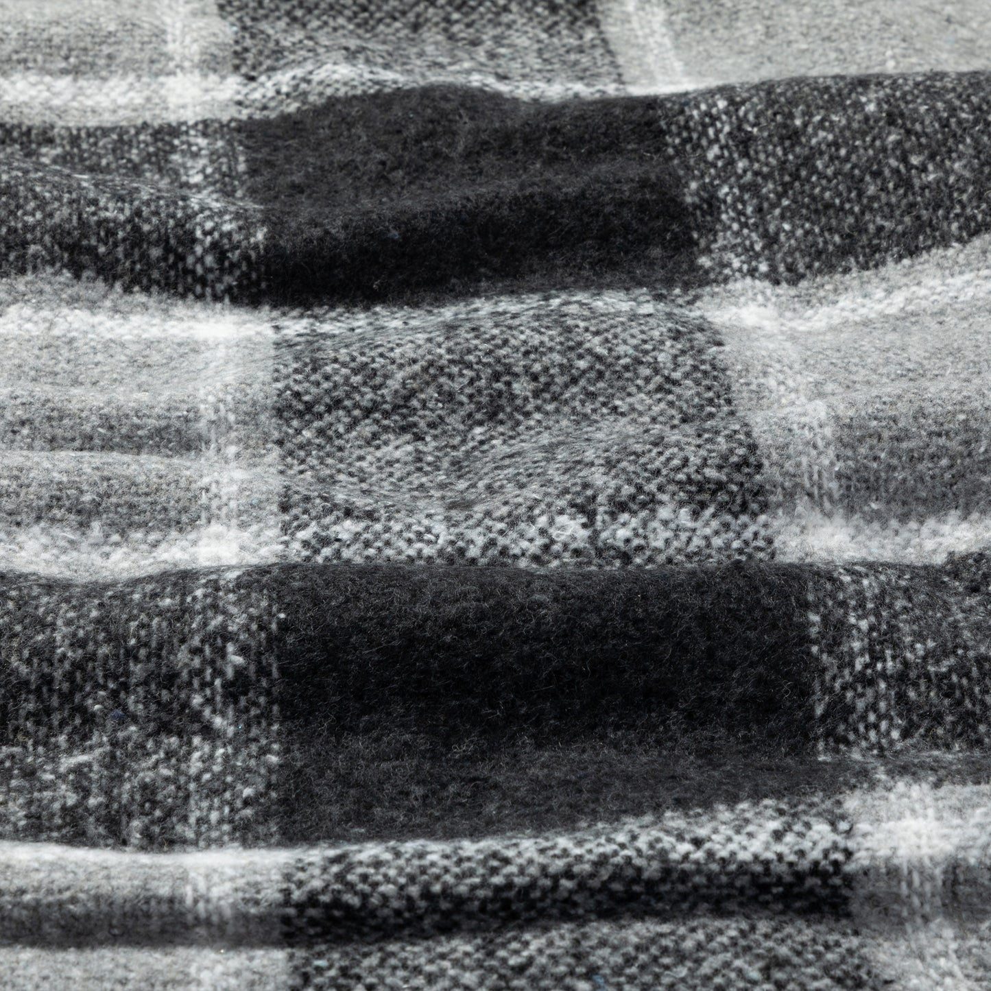 A close-up of a black and white plaid woven blanket, showing the detailed weave and pattern.