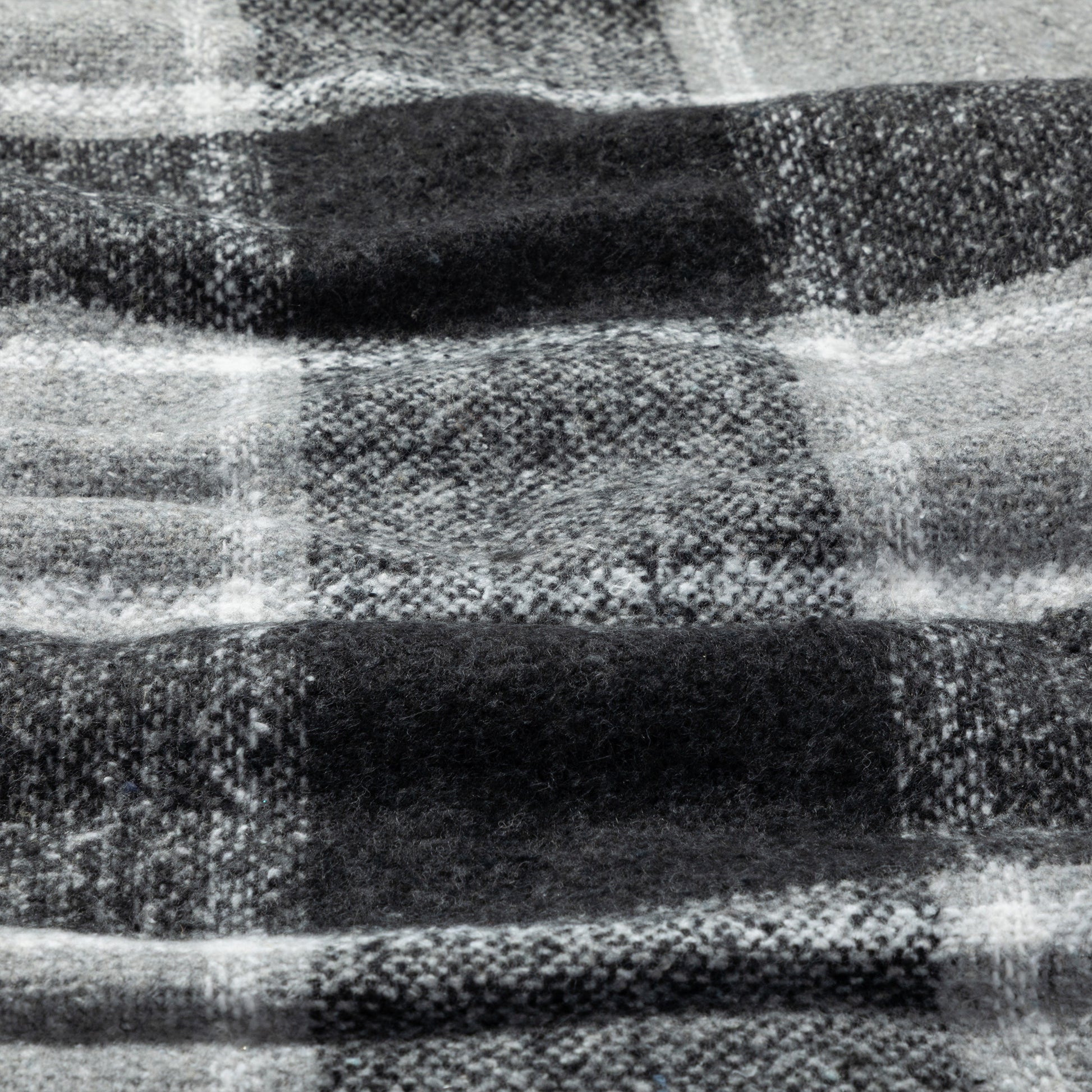 A close-up of a black and white plaid woven blanket, showing the detailed weave and pattern.