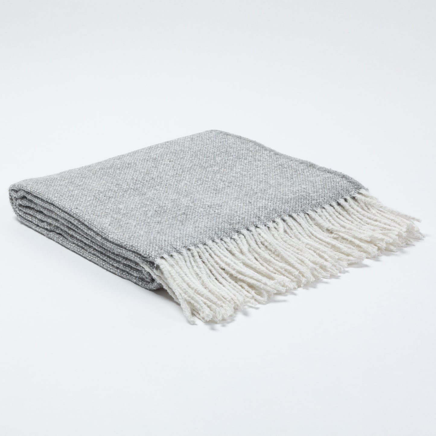 Gray and white fringed blanket neatly folded on a light background.
