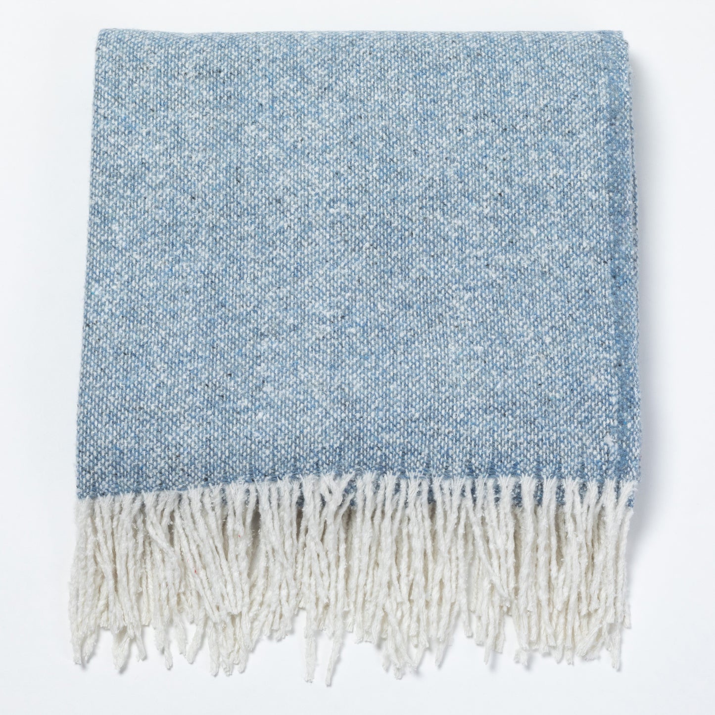 A folded woven throw blanket in a heathered light blue and white colorway, featuring a thick cream-colored fringe along the bottom edge, shown against a plain white background.