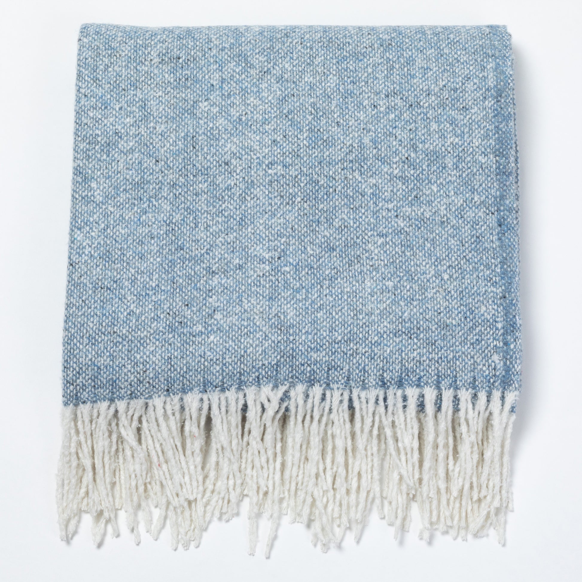 A folded woven throw blanket in a heathered light blue and white colorway, featuring a thick cream-colored fringe along the bottom edge, shown against a plain white background.