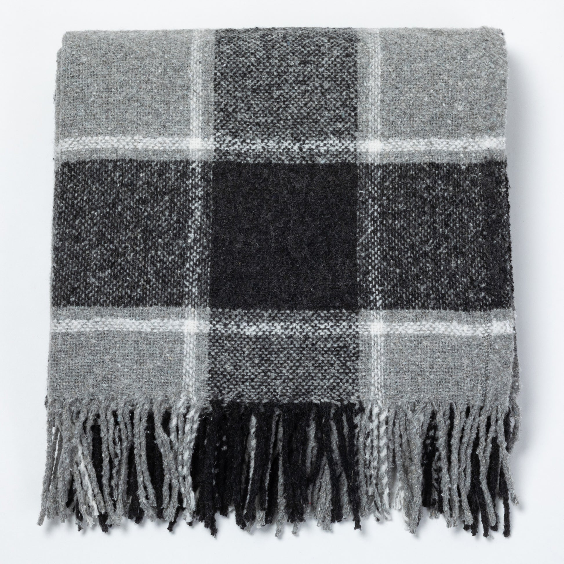Gray plaid throw blanket with fringed edges, folded neatly on a flat surface.