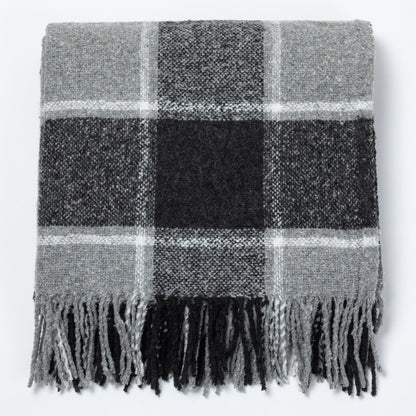 Gray plaid throw blanket with fringed edges, folded neatly on a flat surface.