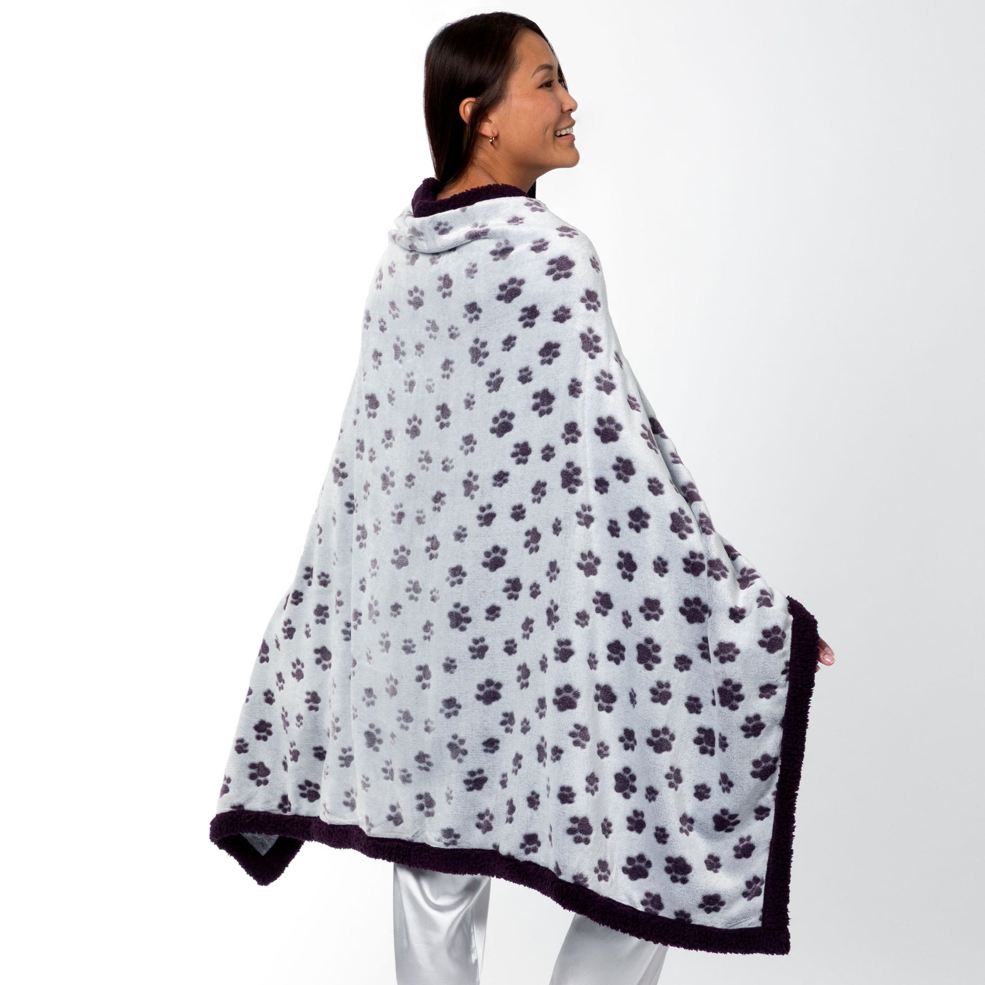 Person wearing a paw print patterned wearable blanket with two front buttons, on a white background.