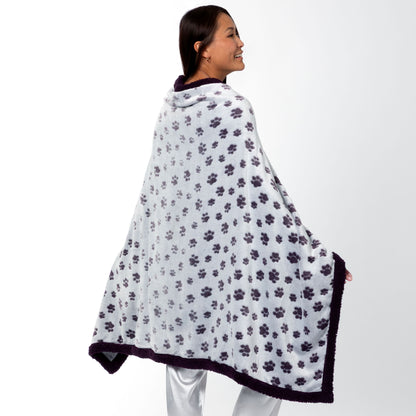 Person wearing a paw print patterned wearable blanket with two front buttons, on a white background.