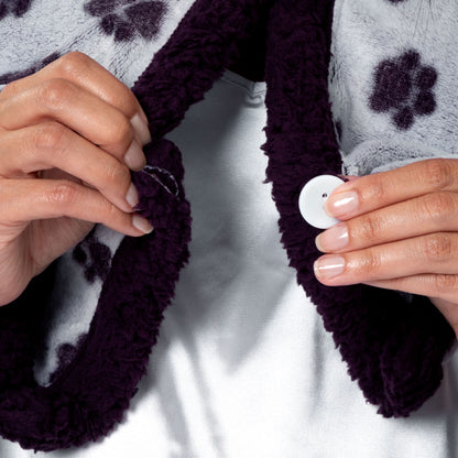 Person wearing a paw print patterned wearable blanket with two front buttons.