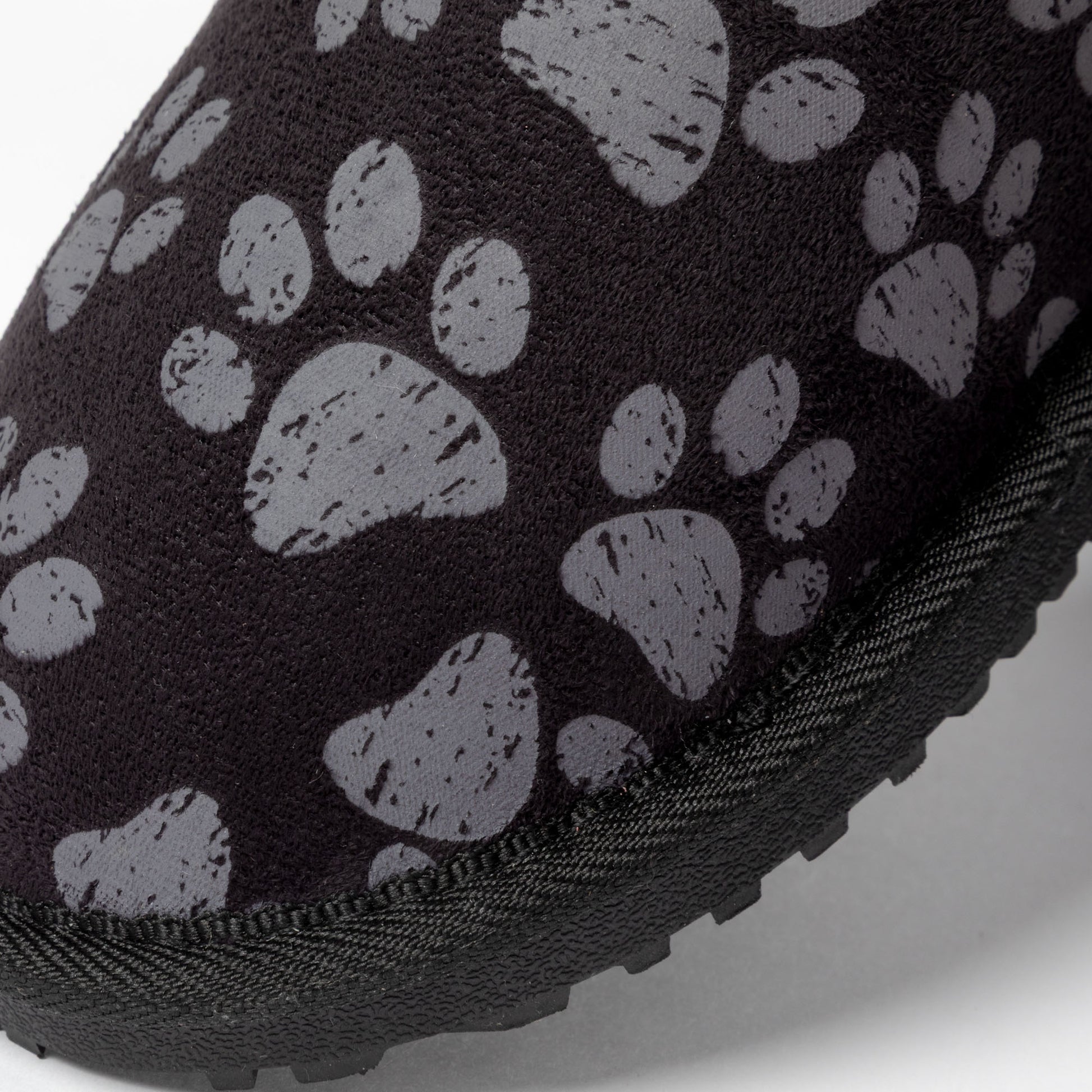 Close-up of a black shoe with gray paw print pattern on a white background