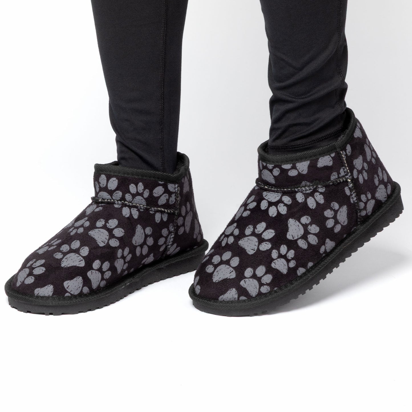 Black boots with gray paw prints worn with black pants on a white background
