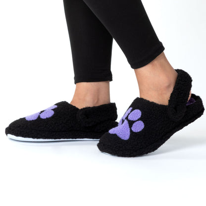 Black slippers with purple paw prints worn by a person on a white background