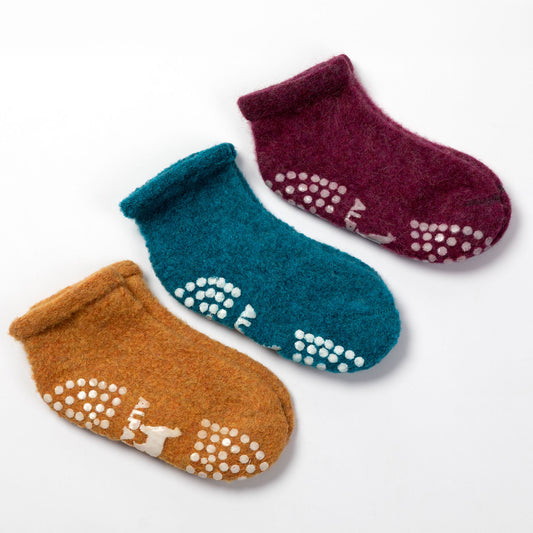Three fuzzy ankle socks arranged on a white background: one mustard brown, one teal blue, and one burgundy. Each sock has white grip dots and a small white animal motif on the sole.