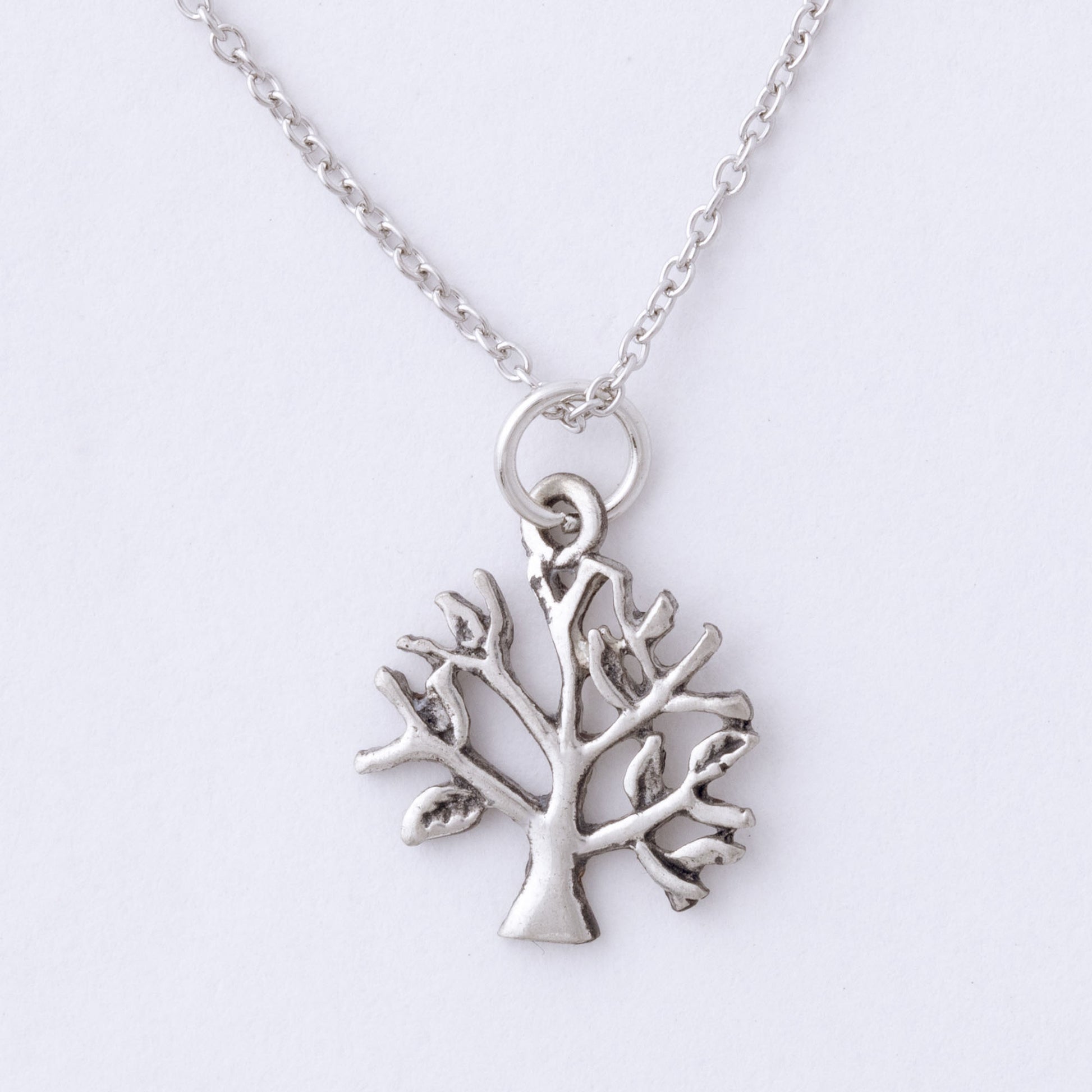 Silver tree-shaped pendant on a chain against a white background