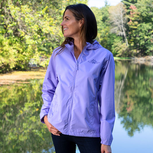 Woman wearing a purple rain jacket with a hidden paw pattern that activates when wet, while outside.