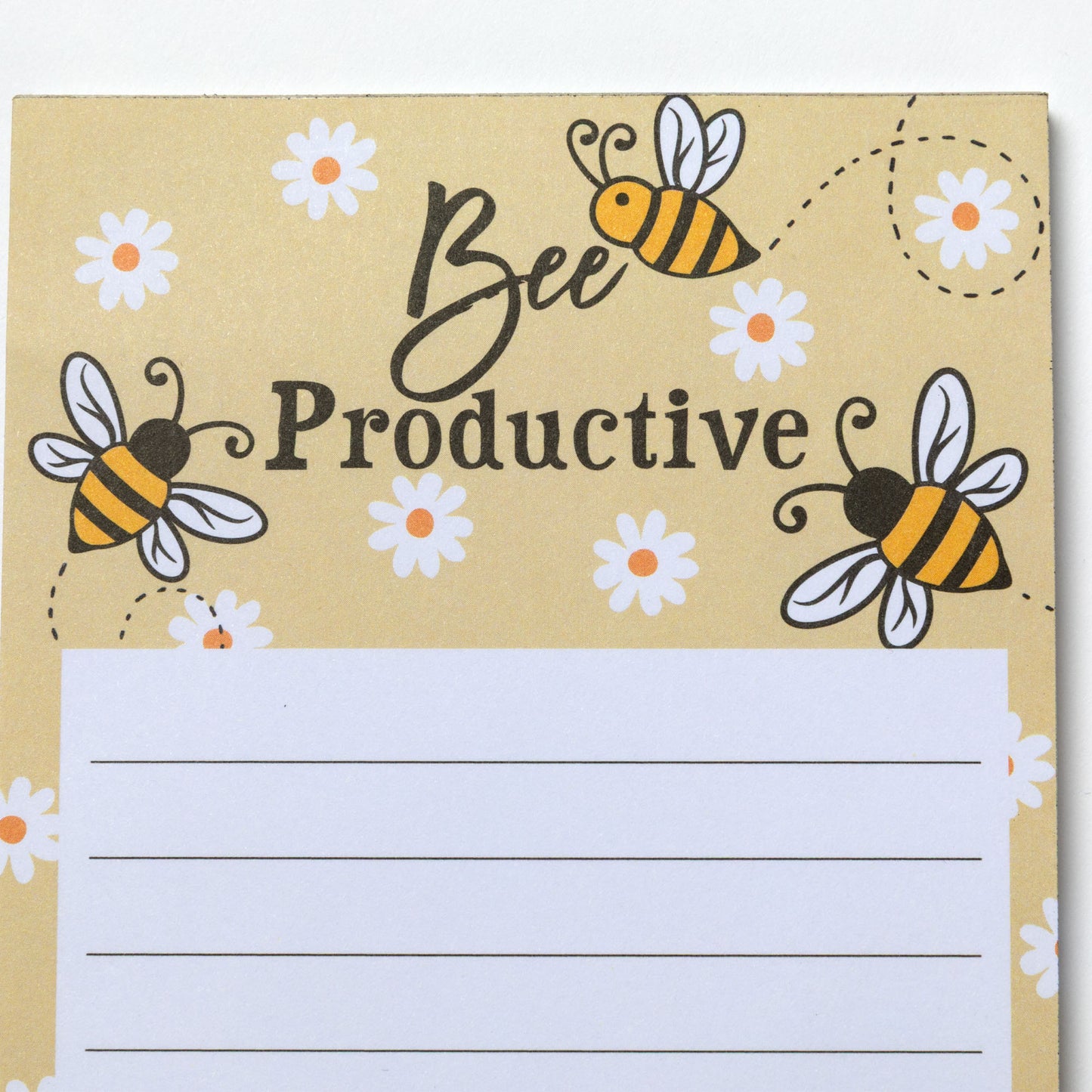Close up of notepad with 'Bee Productive' text and bee illustrations on a light yellow background.