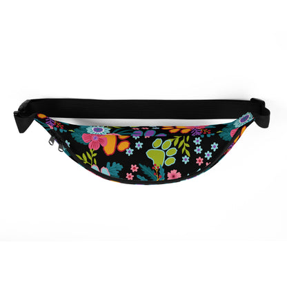 Floral Paw print pattern with a black background on a fanny pack with a black strap. top view.
