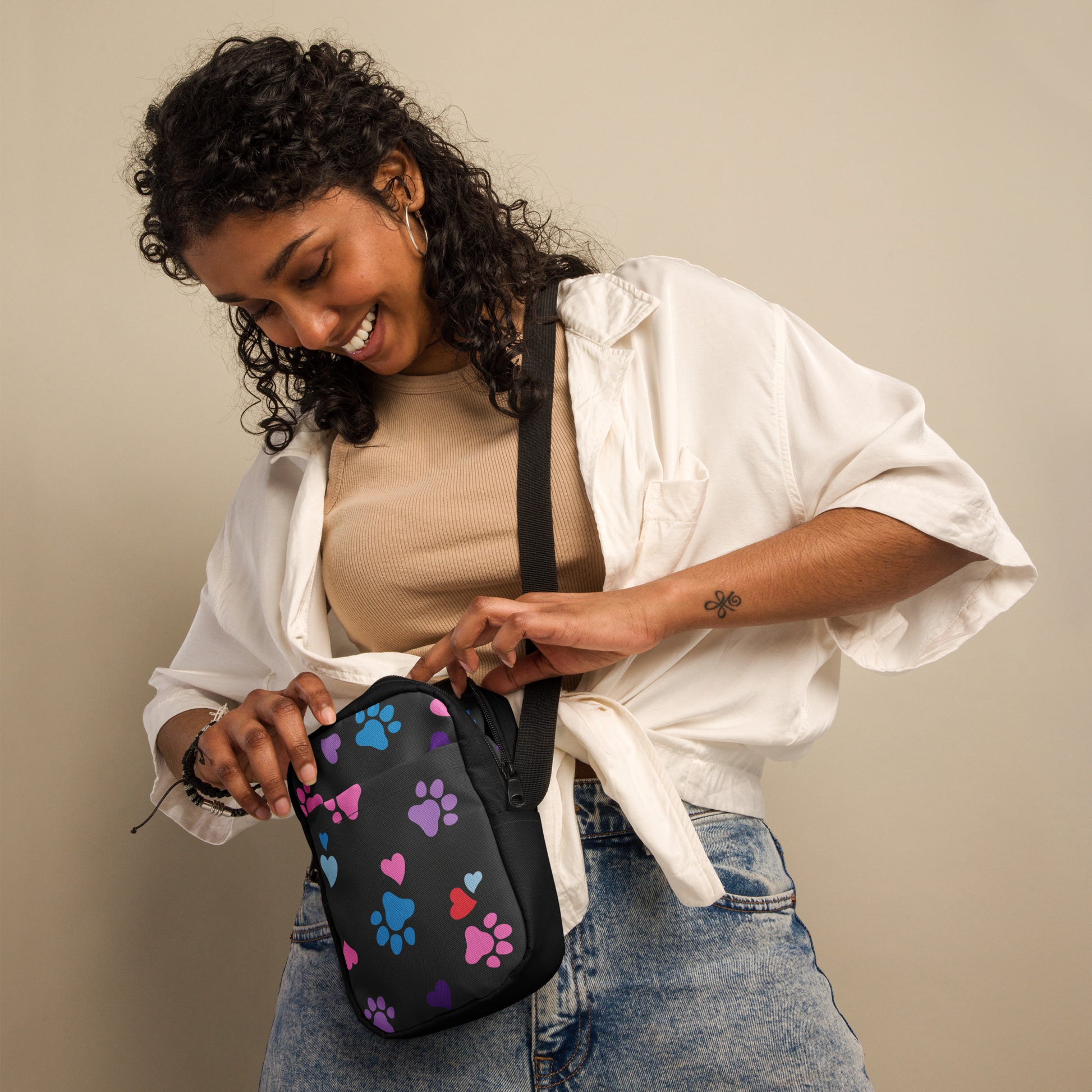 Woman holding a black bag with colorful paw prints against a beige background