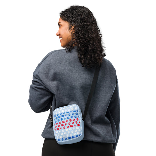 Person wearing a gray sweatshirt with a small blue and red patterned bag on their back against a white background