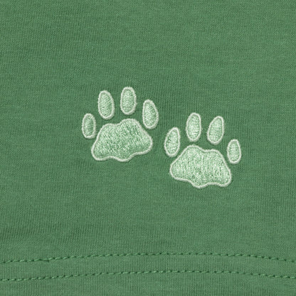 Two light green embroidered paw prints on a green fabric background