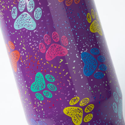 A close-up of a purple insulated tumbler with a colorful dog paw print pattern and multicolored confetti speckles, shown against a white background.