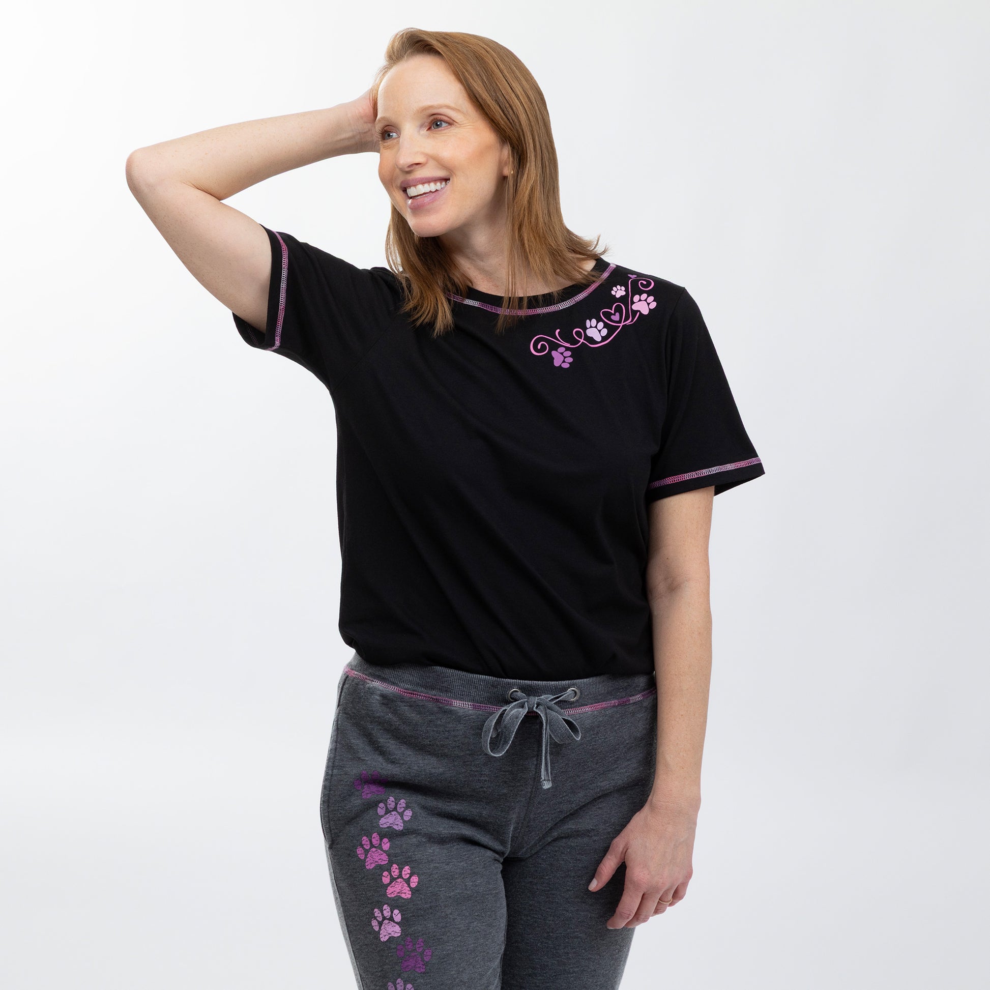 Woman wearing a black t-shirt with purple trim and floral and paw design on a white background