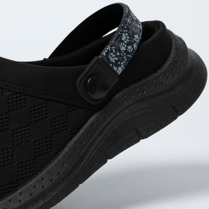 Black clog shoe with a strap on a light gray background