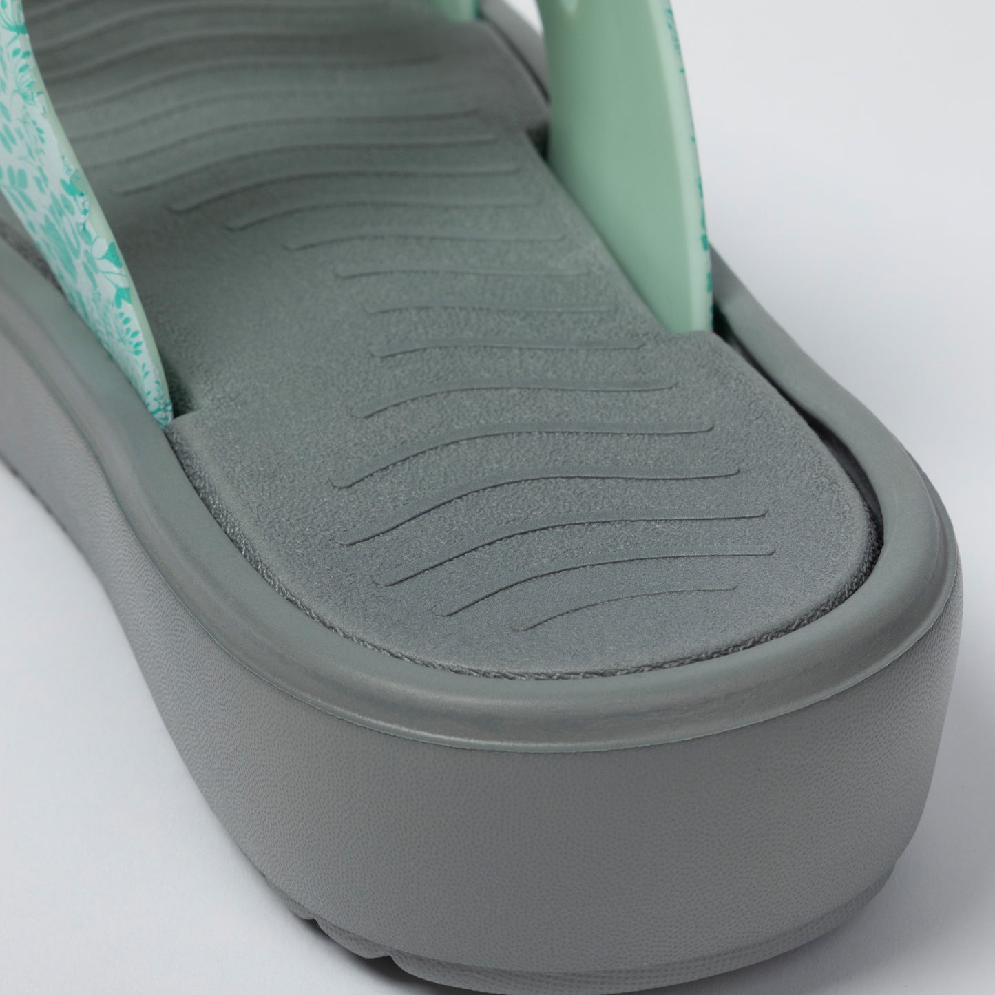 Close-up of a sandal with a textured sole on a light gray background
