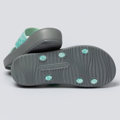 Pair of gray sandals with green accents on a light gray background