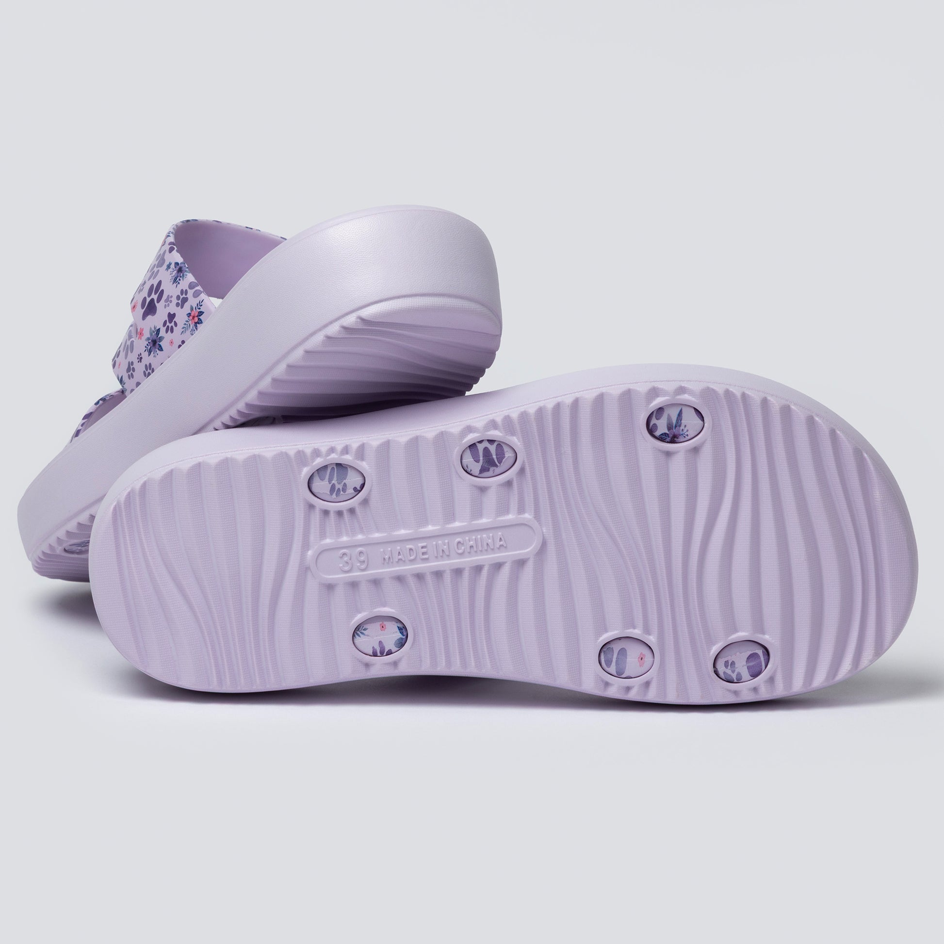 Purple sandals with floral pattern on a light gray background