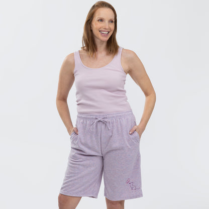 Woman wearing a light purple tank top and shorts on a white background.