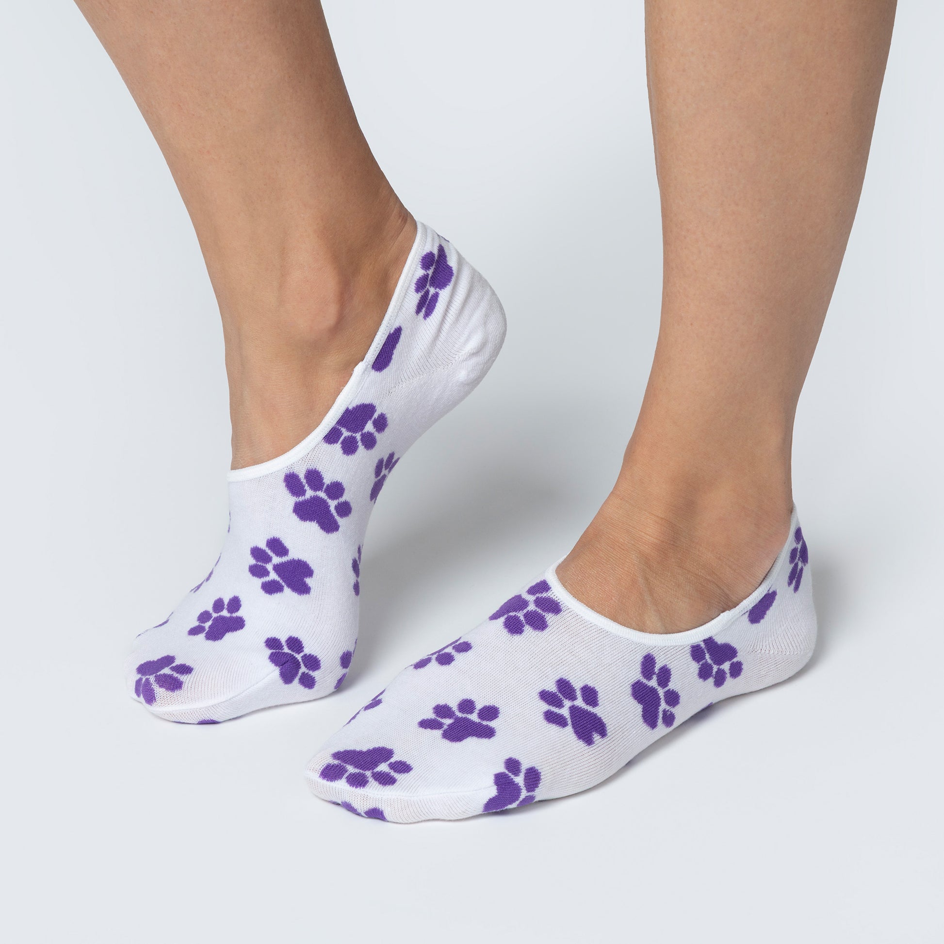 White socks with purple paw prints worn by a person on a light gray background
