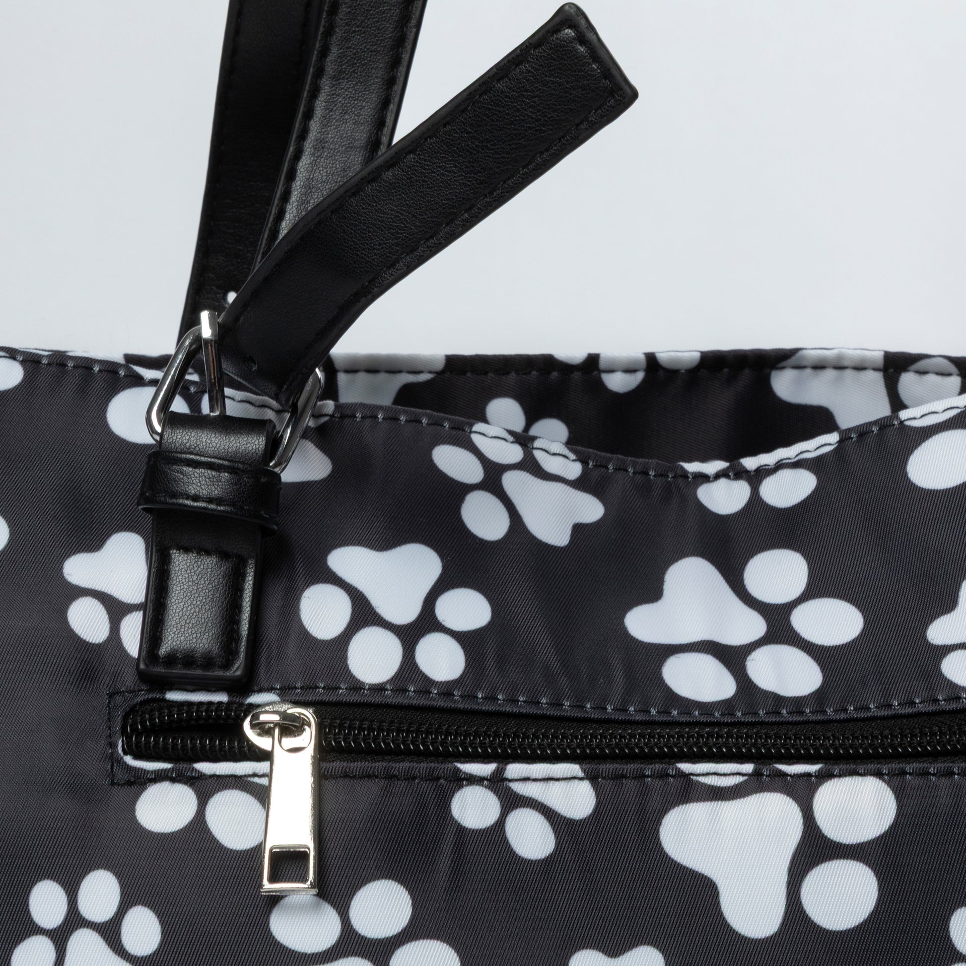 Black bag with white paw prints and a black strap on a light gray background