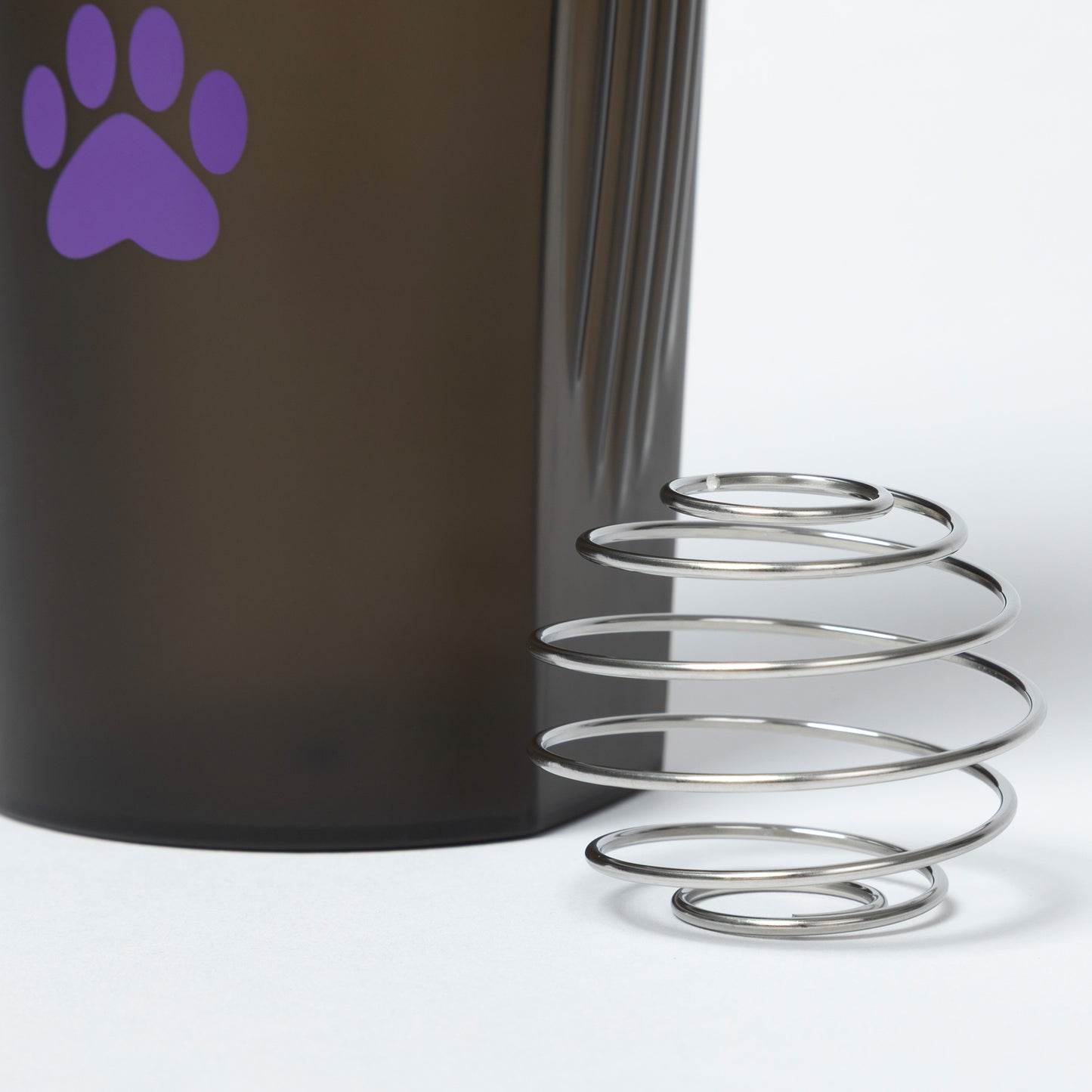 Metallic spring with a dark cylindrical object and purple paw print on a white background