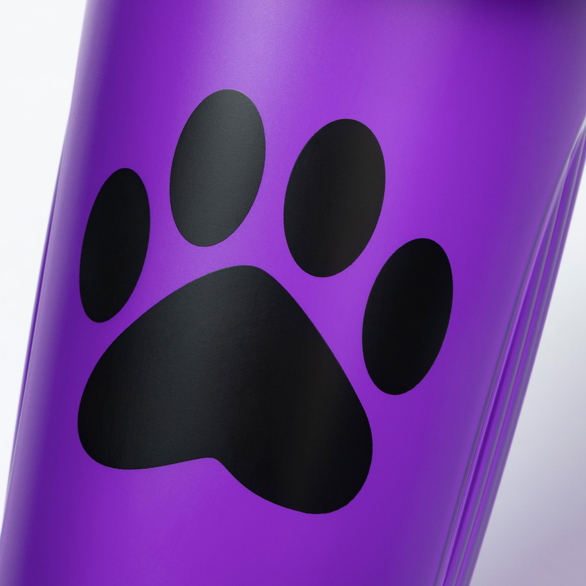 Close-up of a purple shaker bottle with a black paw print design on a white background