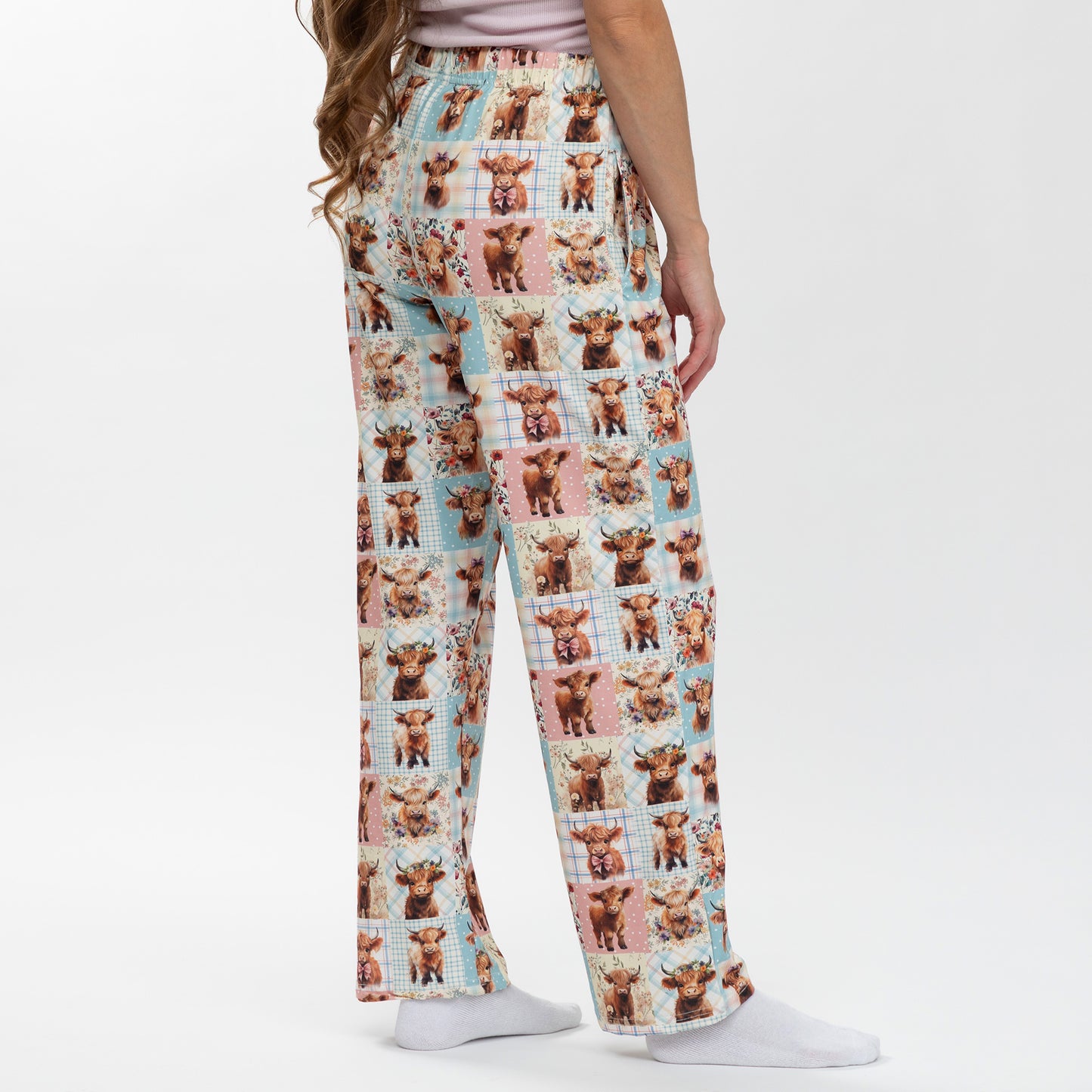Pajama pants with highland cow pattern worn by a person on a white background