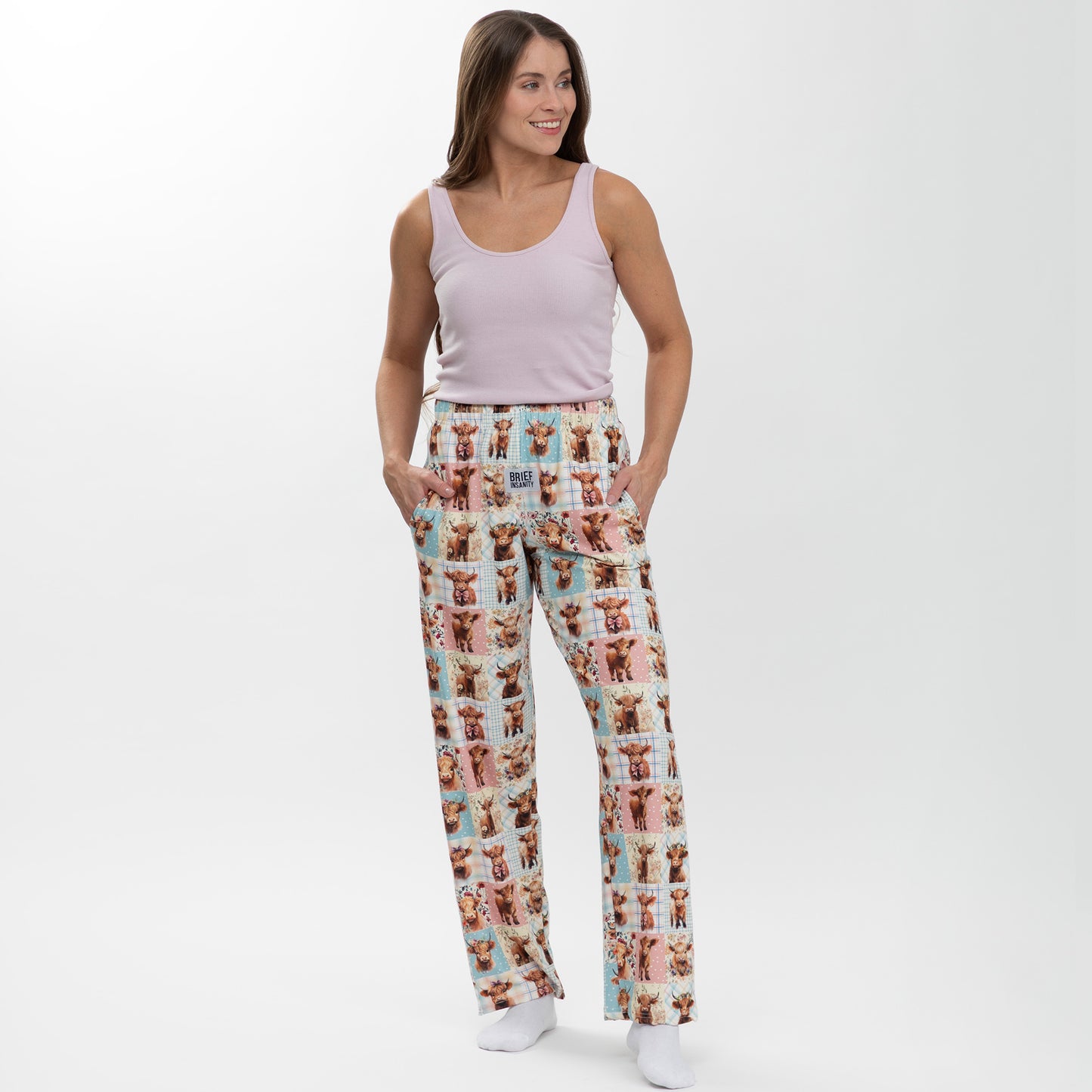 Woman wearing pajama pants with highland cow pattern on a white background