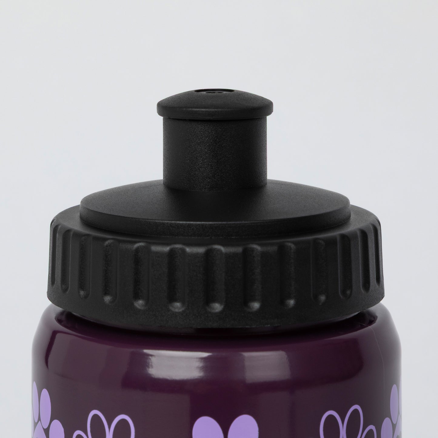 Close-up of a dark purple water bottle with a black flip-top lid and light purple heart pattern, shown against a light gray background.