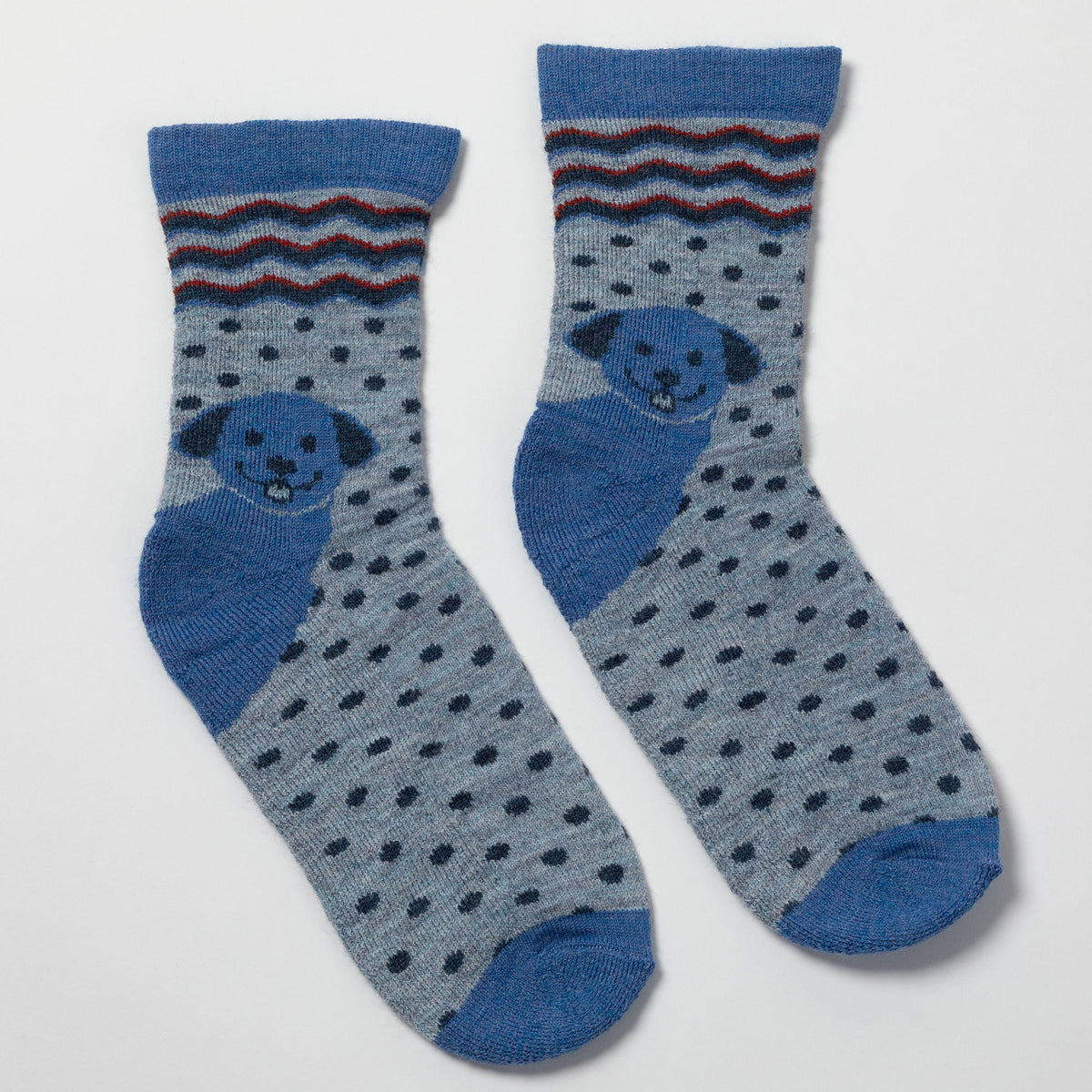 A pair of crew socks in heathered light blue with dark blue polka dots, featuring a blue dog face motif and a striped cuff with blue, red, and brown accents.