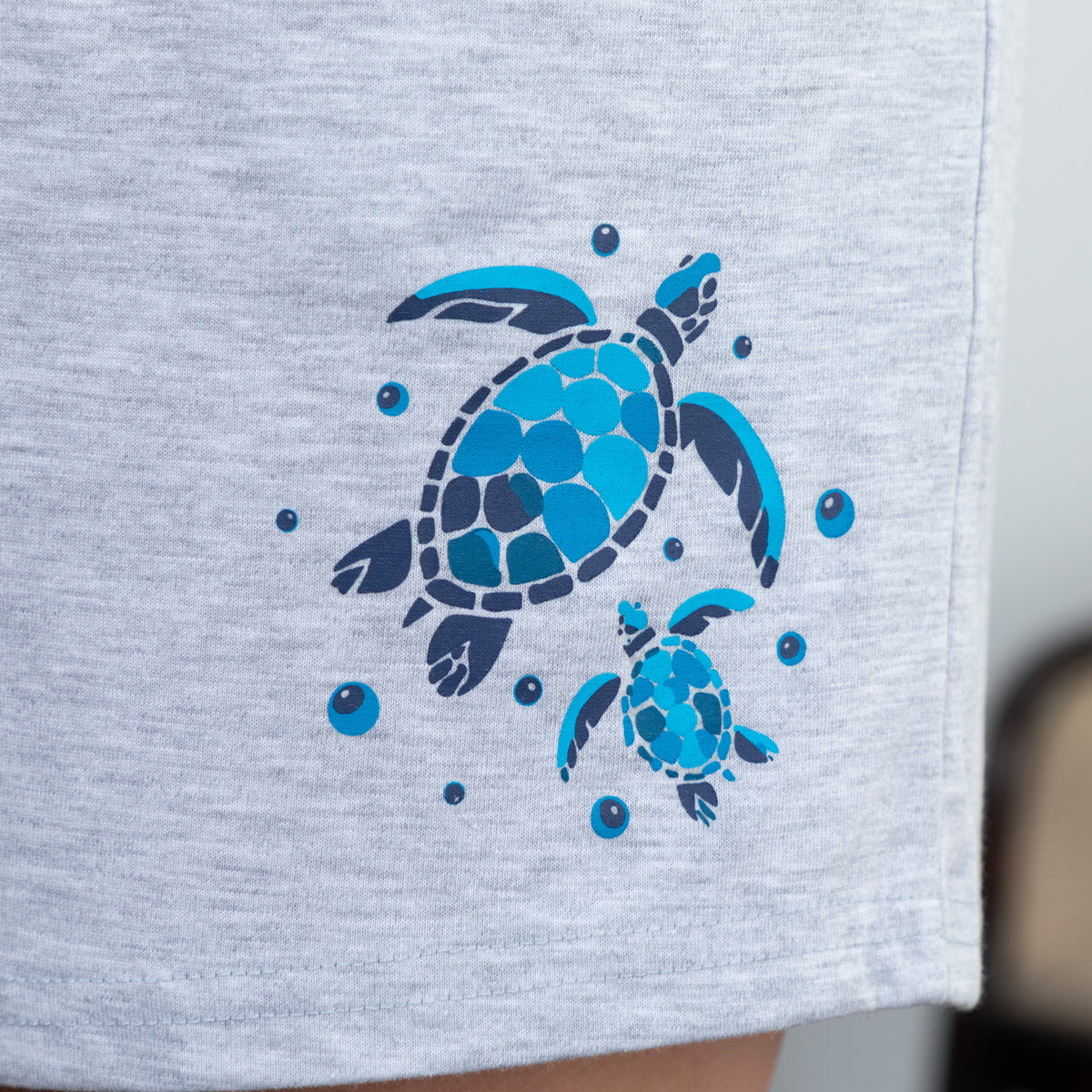 Gray shorts with blue mom and baby sea turtle design on a light gray background