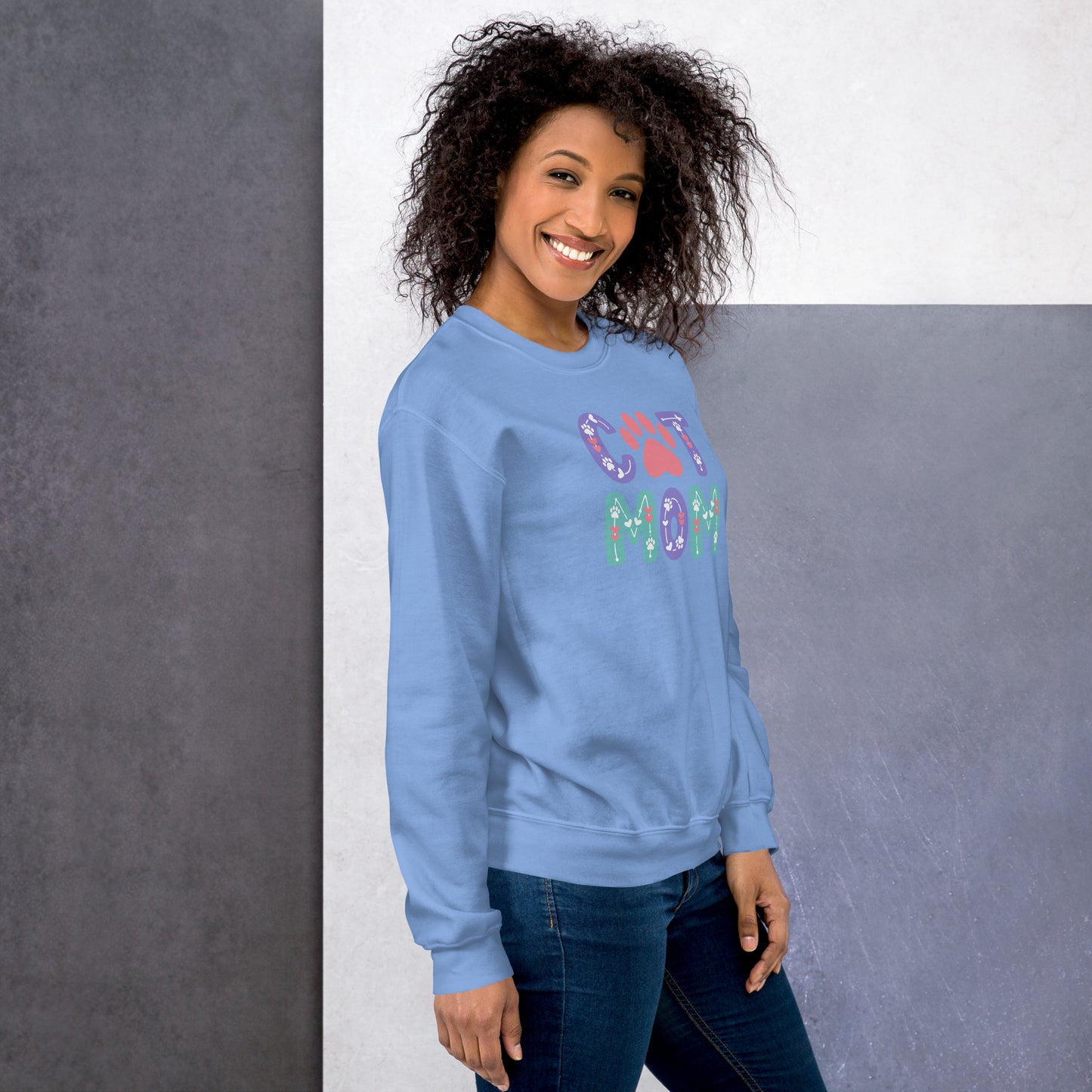 Woman wearing a blue sweatshirt with colorful text and graphics on a gray background