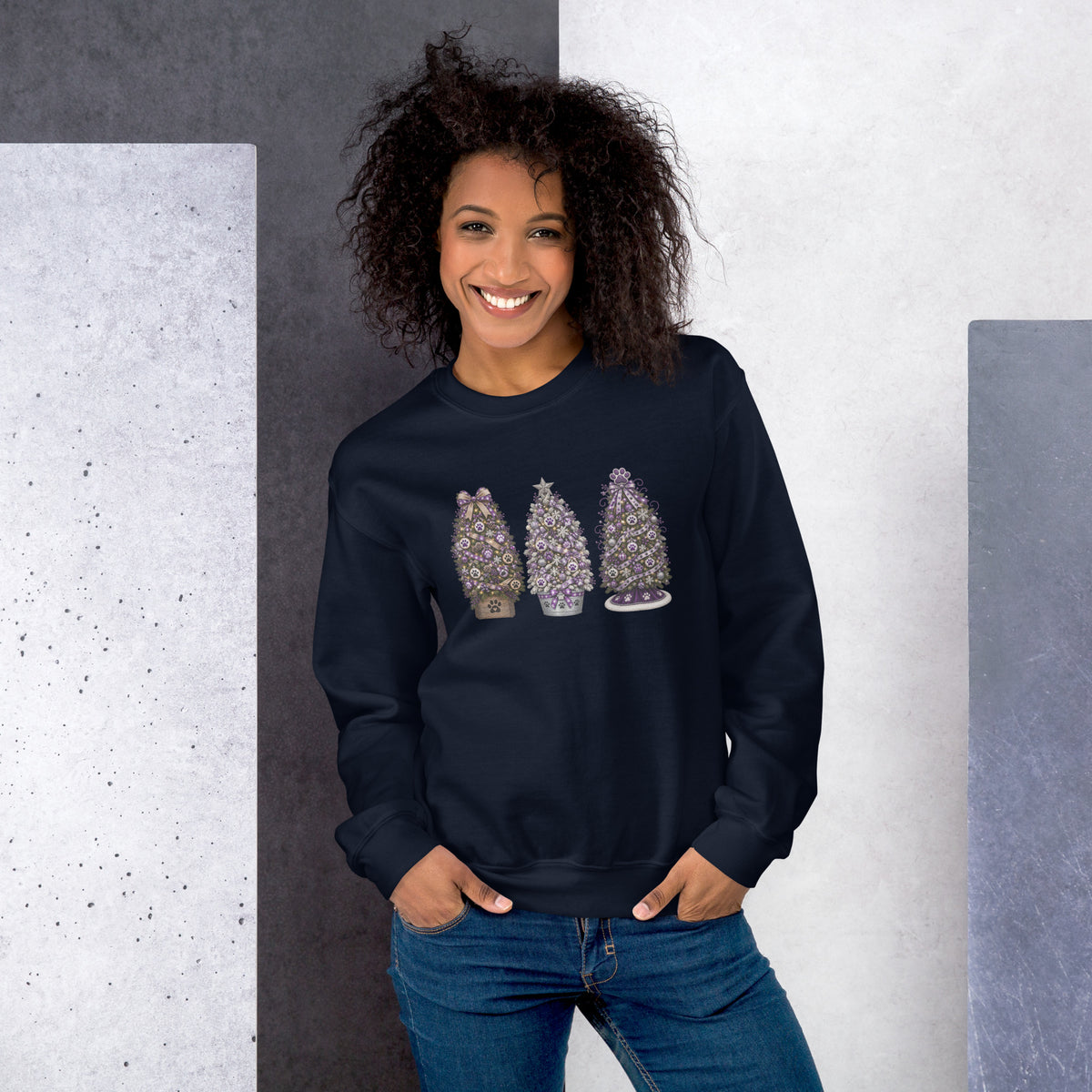 Woman wearing a navy sweatshirt with colorful text standing against a gray and white wall.